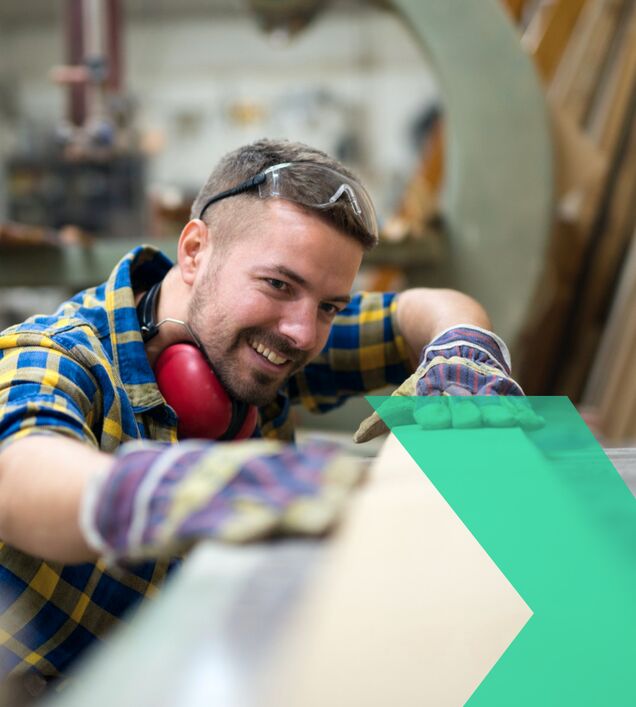 Holzbearbeitung in Tischlerei: Mitarbeiter arbeitet an Holzplatte mit Maschine – Arbeitsschutz und Präzision im Holzhandwerk im Raum Chemnitz