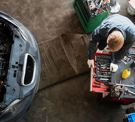 Mechaniker prüft Auto im Werkstattbetrieb – Arbeitssicherheit bei Hebebühnen und Gefahrstoffen in Chemnitzer Autohäusern