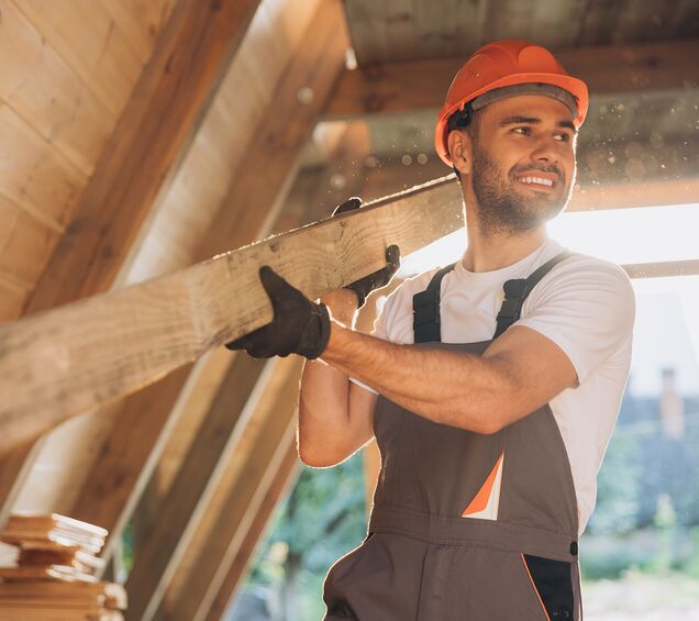 Handwerker hebt Holzplatte ergonomisch – Arbeitsschutz und rückenschonende Techniken im Tischlereibetrieb Region Chemnitz